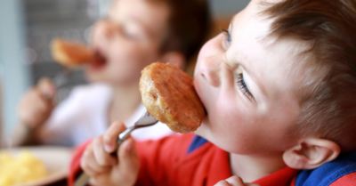 Image included is a photo of a child eating a chicken nugget